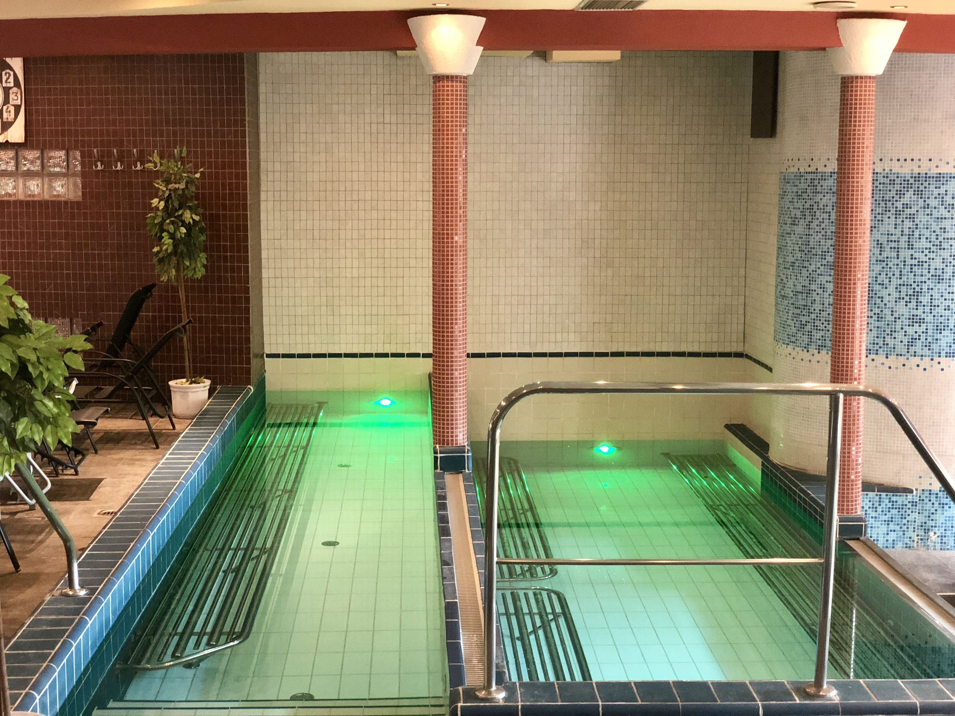 Una piscina con paredes de azulejos y barandilla de metal.