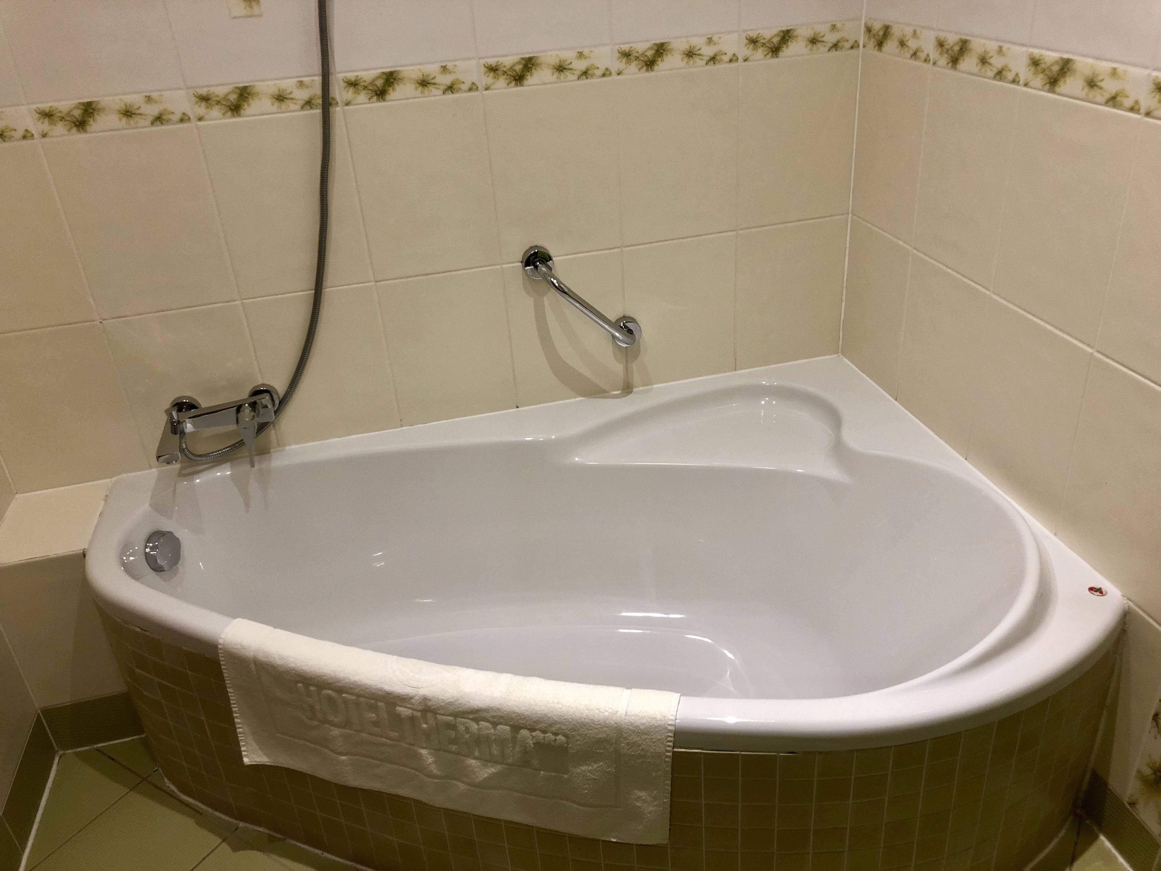 Ein Badezimmer mit einer Badewanne, einer Duschbrause und einem Handtuch, das an der Seite hängt.