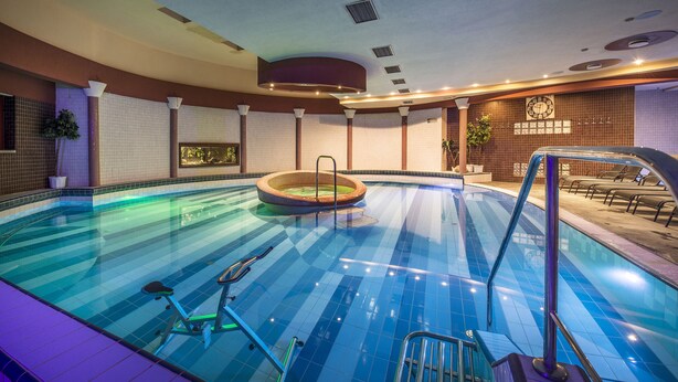 An indoor swimming pool with a hot tub, exercise equipment, and a clock on the wall. - Therma Nea Dunajská Streda (Dunajska Streda)