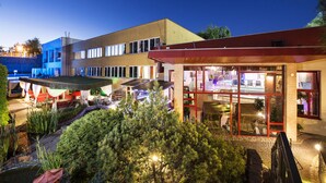 A modern building with a glass facade, outdoor seating area, and a well-lit patio. - Therma Nea Dunajská Streda (Dunajska Streda)