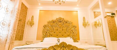 Un dormitorio lujoso con una cama grande y ornamentada, un candelabro y detalles en dorado.