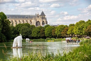 A historic building with Gothic architecture, a large clock, and a lake with boats and a white elephant sculpture. - Camping de Châlons-en-Champagne (Chalons-en-Champagne)