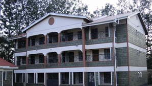 A multi-story building with a flat roof, multiple balconies, and a large open courtyard. - Easy Sleep Guesthouse (Kitale)