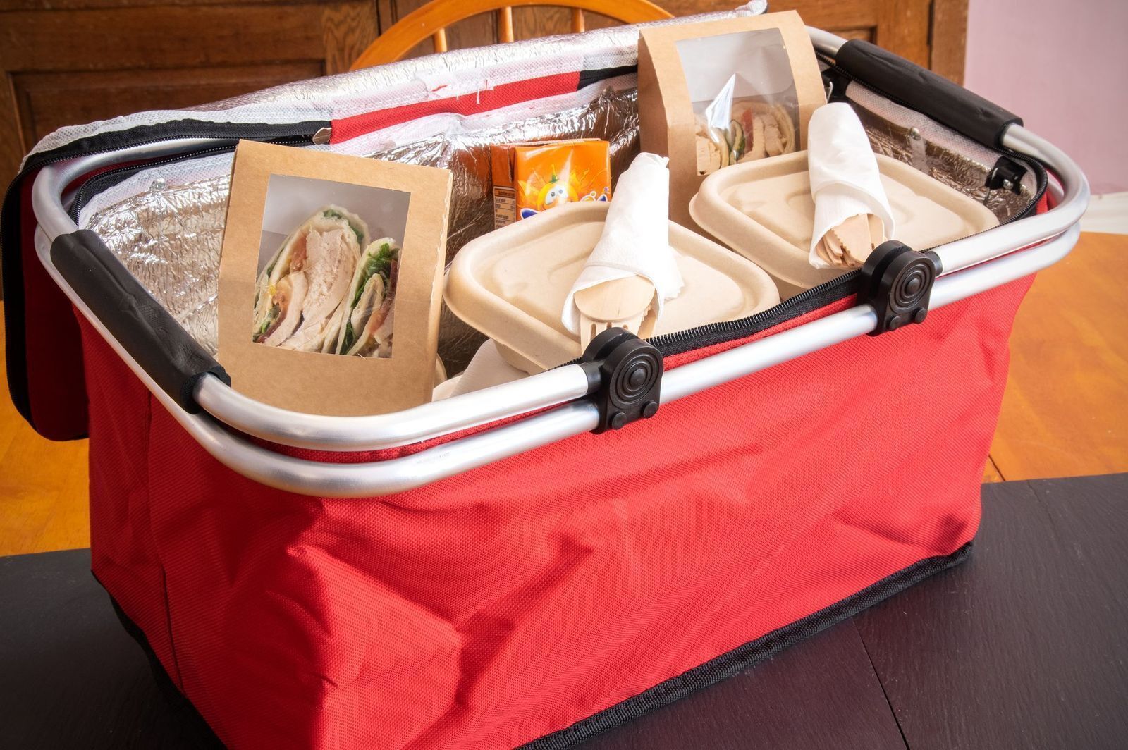 A red suitcase with a zipper, containing a picture of sandwiches, a bottle, and a wooden object.