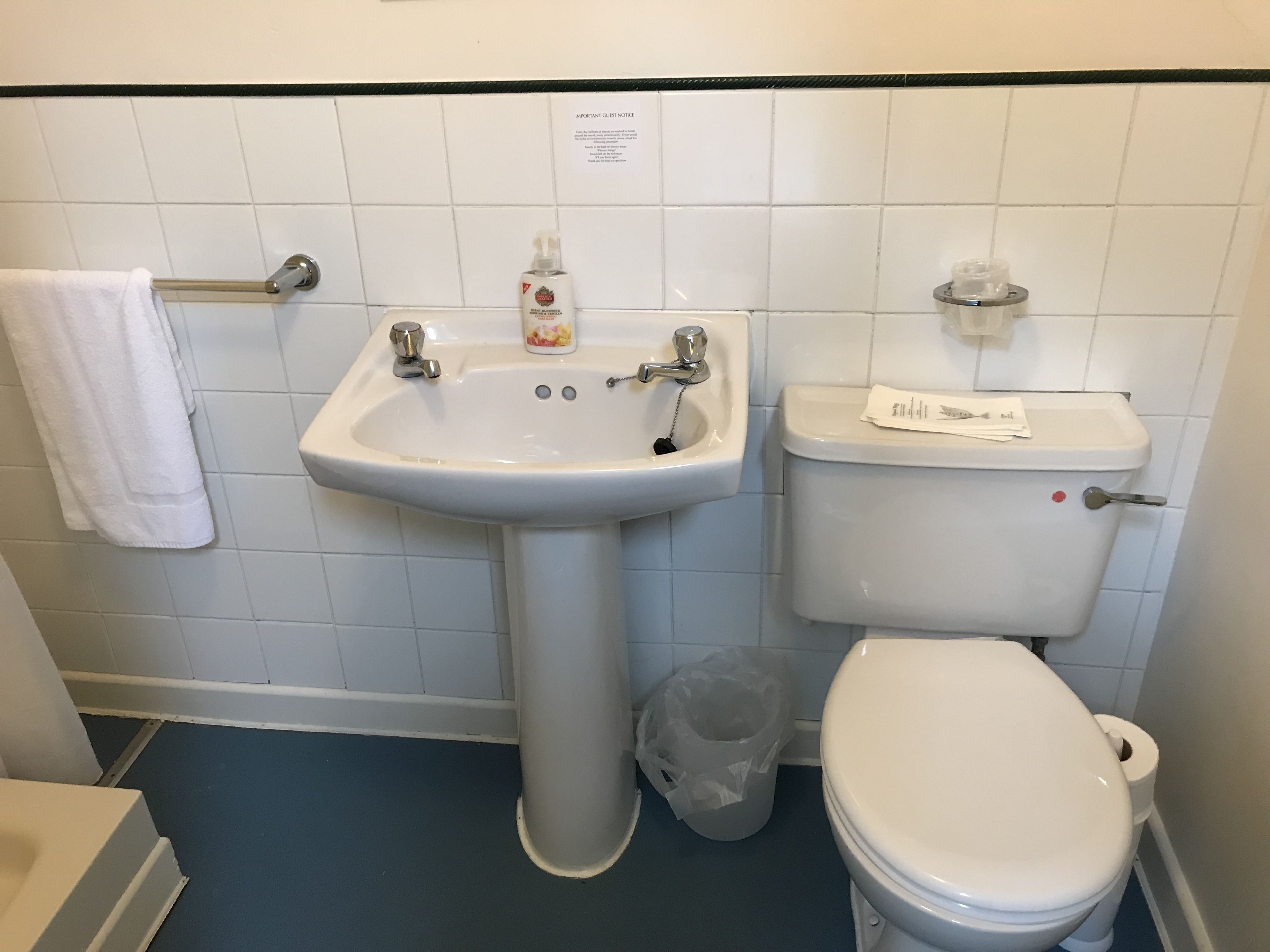 A bathroom with a white sink, toilet, and a towel rack.