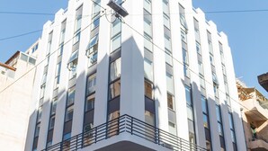 A modern building with a white facade, large windows, and a balcony with a metal railing. - Tins Athens (Athens)