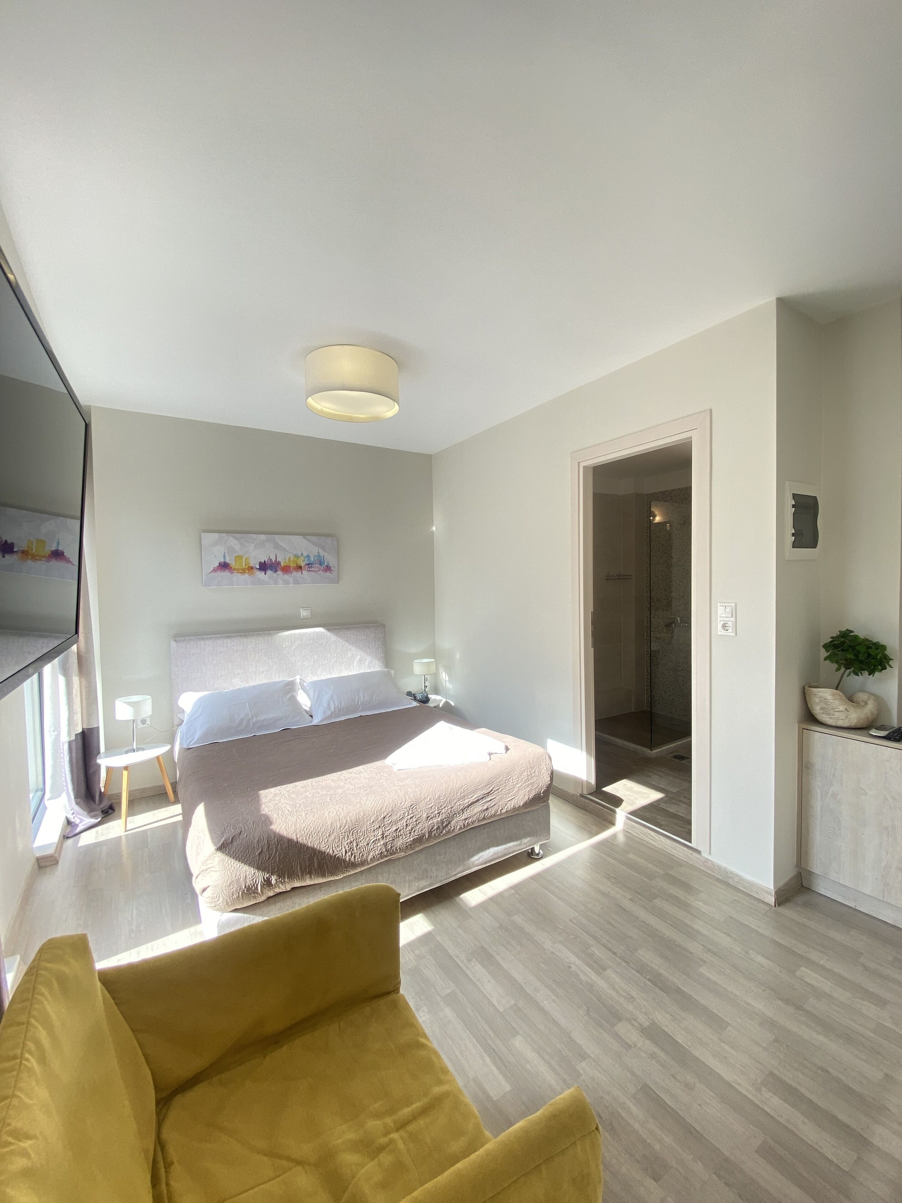 A modern bedroom with a large bed, a bedside table, a lamp, and a window.
