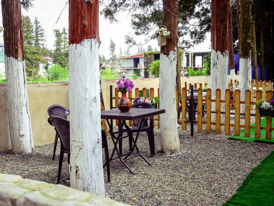 Un'area patio esterna con tavolo e sedie, circondata da pali e recinzione in legno.