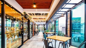 A modern indoor space with tables and chairs, large windows, and a view of the city. - Penyos Residence (Bangkok)