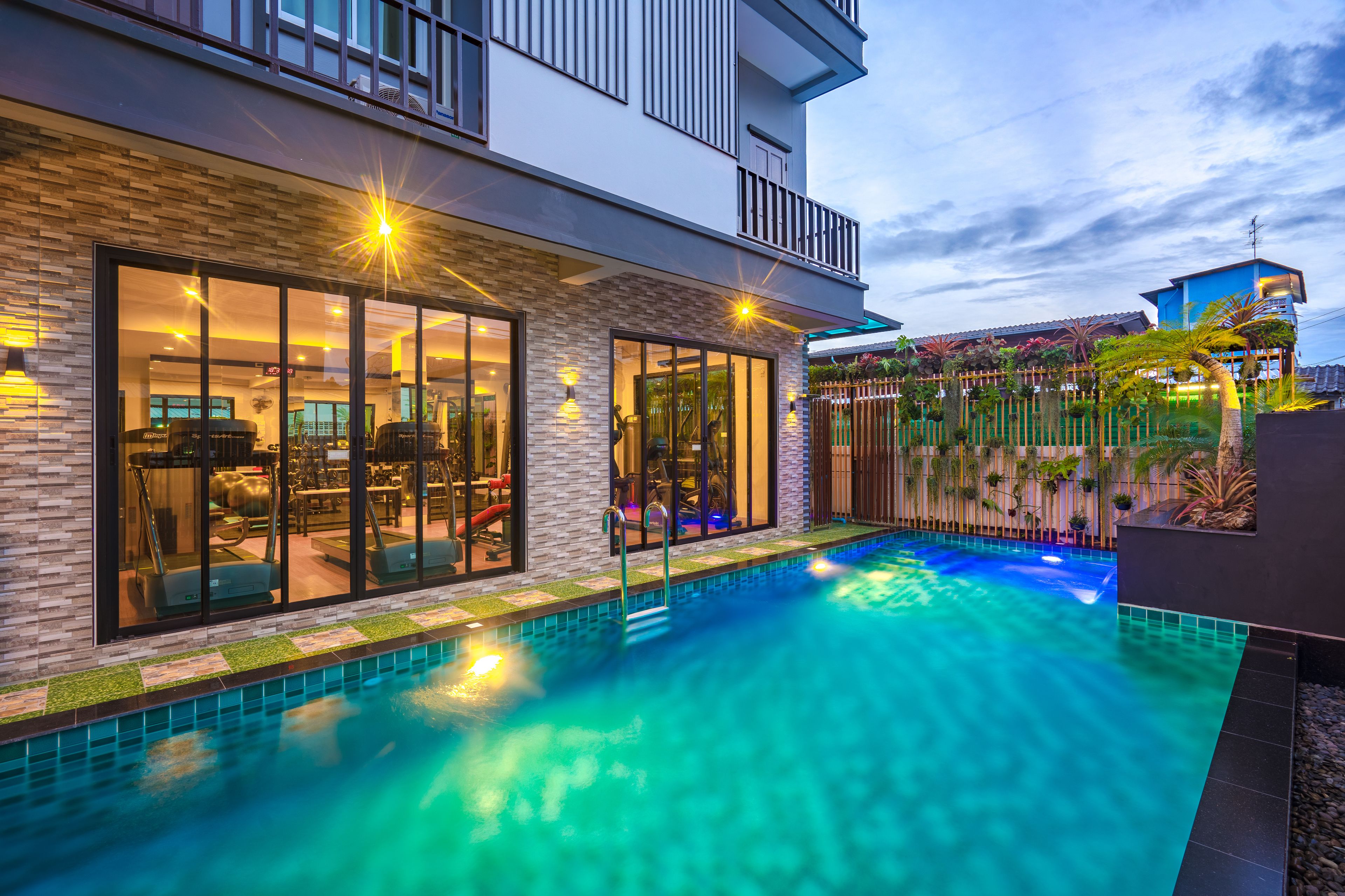 A modern house with a swimming pool, large windows, and outdoor lighting.