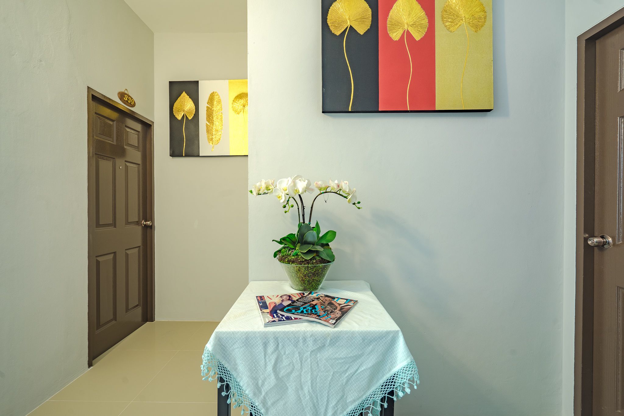 A hallway with a door labeled "339", a table with a magazine, and a potted plant.