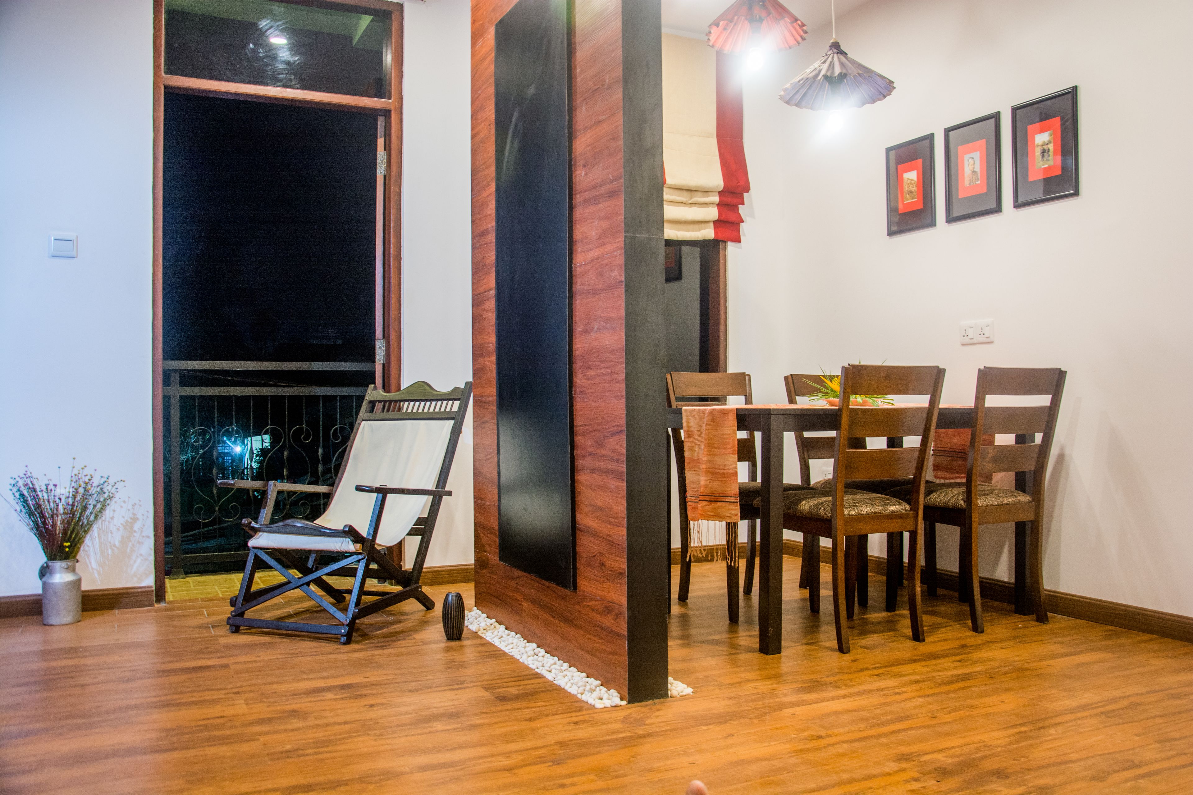 A dining area with a wooden table and chairs, a black accent wall, and a large window with a view.