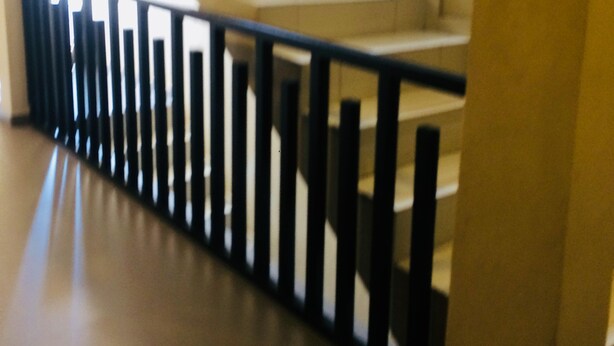Una escalera con barandilla negra que sube a un piso superior.