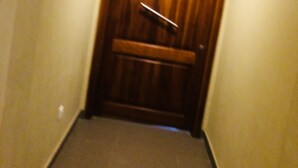 Un estrecho pasillo con una puerta de madera al final.