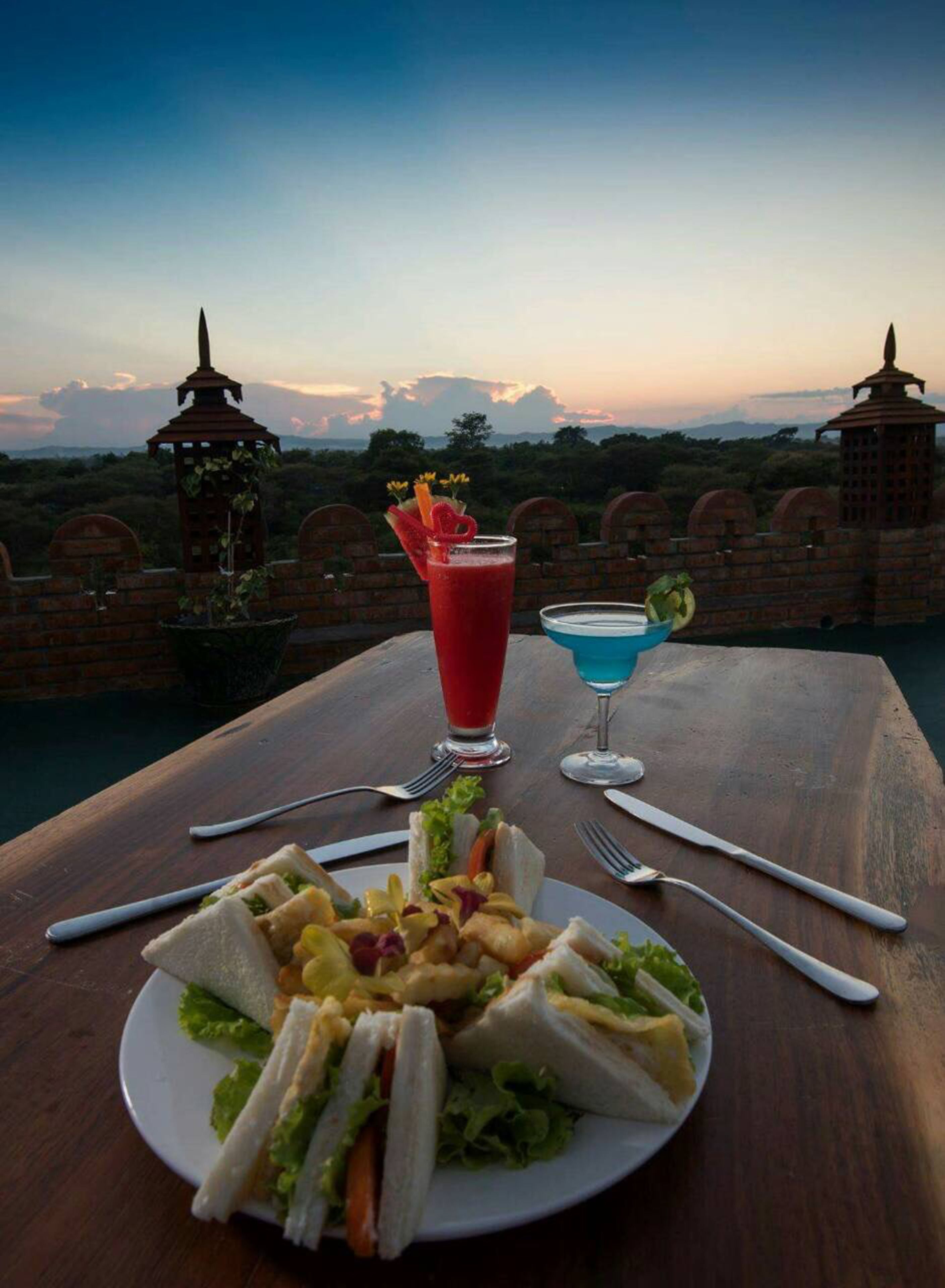 A meal setup with sandwiches and drinks on a table with a scenic view in the background.