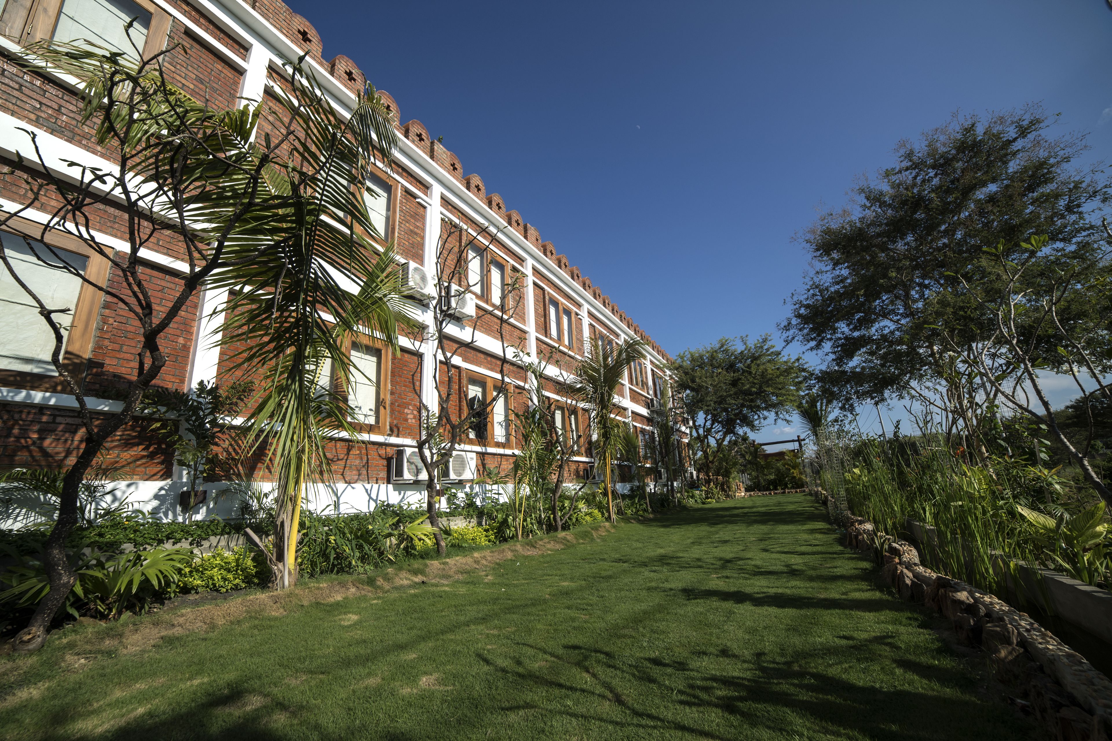 A row of brick buildings with white trim and a well-maintained lawn in front.