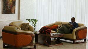 A living room with two sofas, a coffee table with a floral centerpiece, and a painting on the wall. - Marcen Addis Hotel (Addis Ababa)