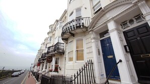 A row of white buildings with black iron balconies, a blue door, and a sign for 'Guffin's'. - New Steine Apartment Sea View by Brighton Holiday Lets (Brighton)