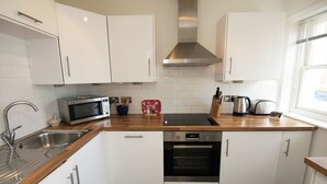 A modern kitchen with white cabinets, stainless steel appliances, and a wooden countertop. - New Steine Apartment Sea View by Brighton Holiday Lets (Brighton)