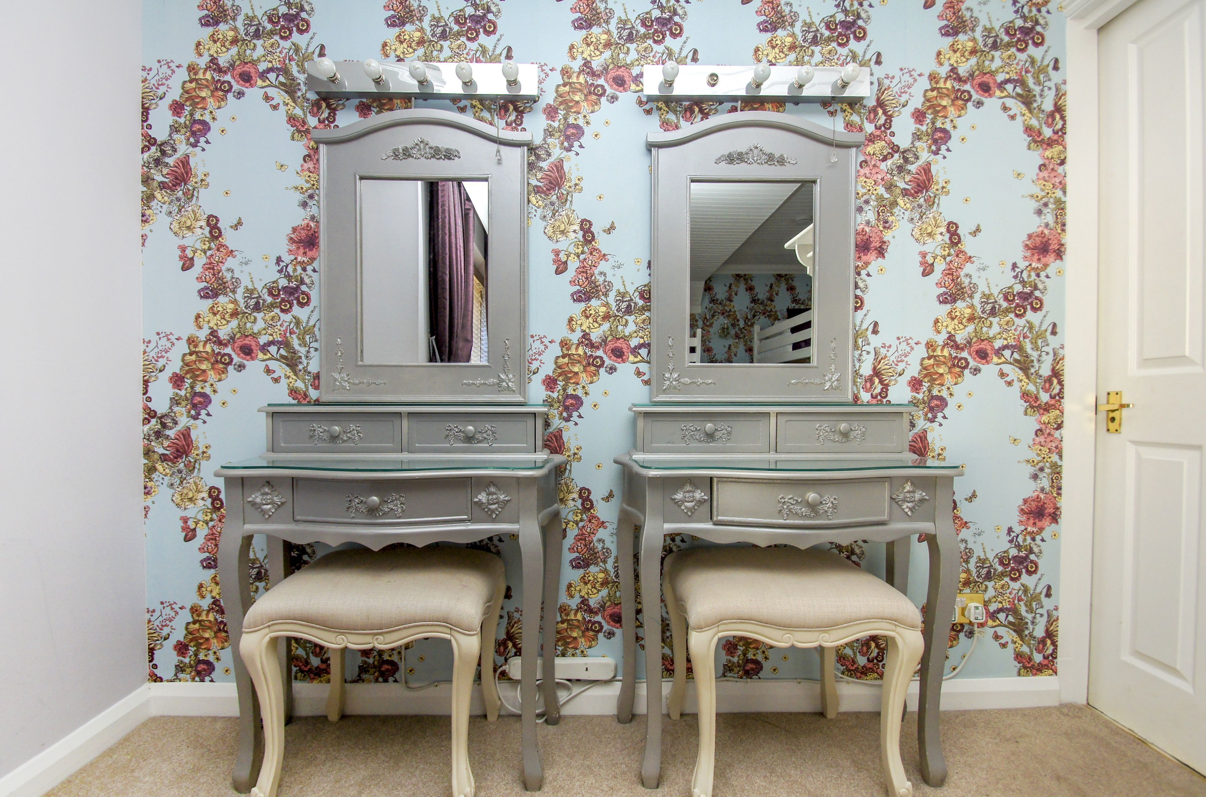 Quarto com duas bancadas de toucador, cada uma com espelho e cadeira.