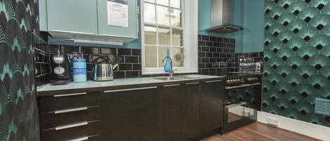 A modern kitchen with dark cabinetry, a window, and a patterned wall.