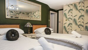 Ein Hotelzimmer mit zwei Betten, einem großen Spiegel, einer Lampe und einer Tür zu einem weiteren Raum.
