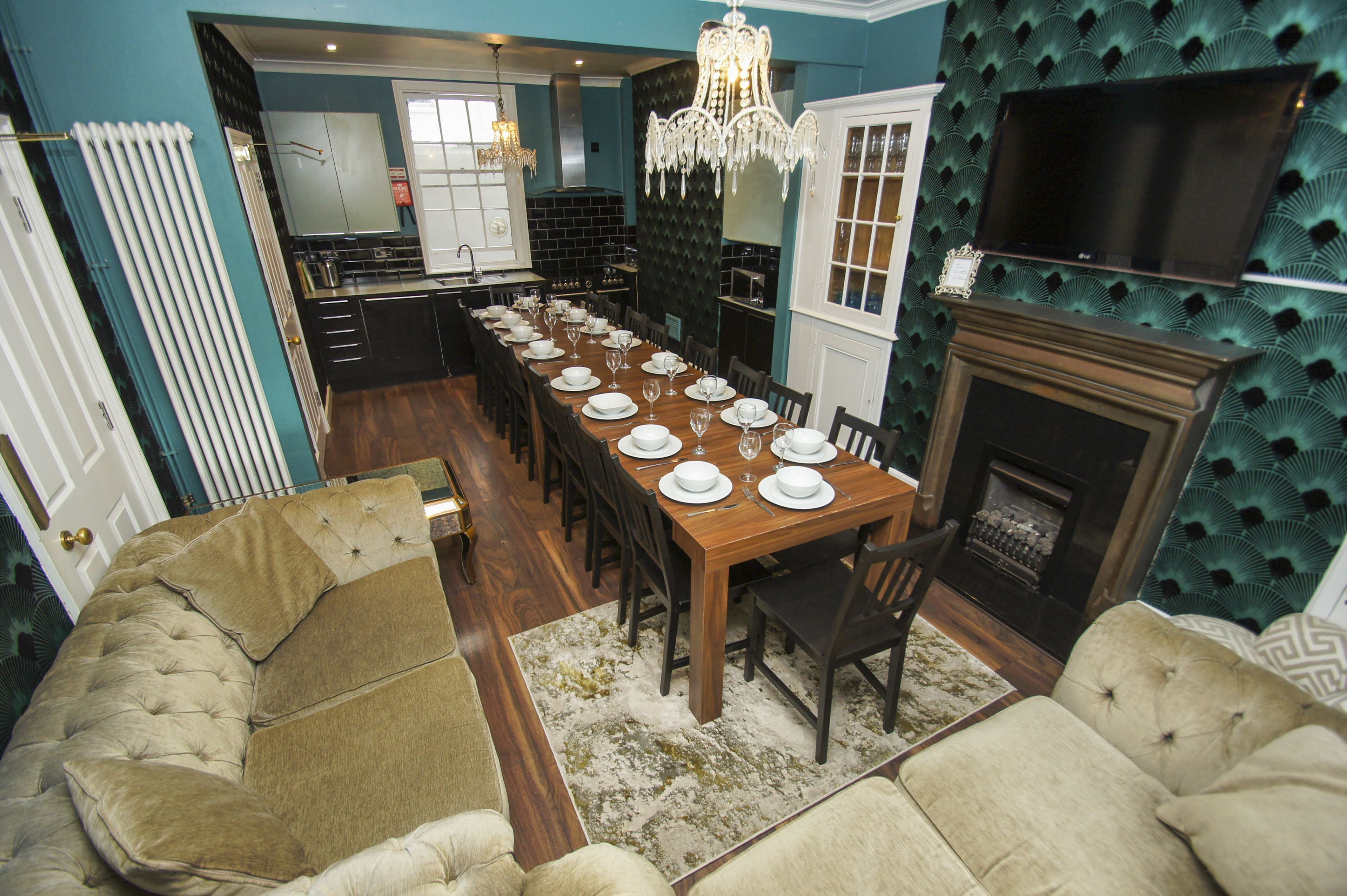 A dining area with a long wooden table set for a meal, flanked by two sofas and a fireplace.