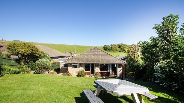 A house with a tiled roof, a front porch, and a grassy backyard with a picnic table. - Dean Court Garden Parking by Brighton Holiday Lets (Brighton)