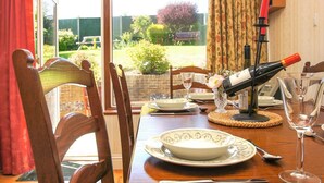 A dining table set with plates, a wine bottle, glasses, and a vase with flowers. - Dean Court Garden Parking by Brighton Holiday Lets (Brighton)