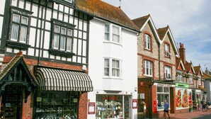 A row of traditional buildings with shops on the ground floor, including a visible storefront with a sign that reads "Serendipity Home Sweet Home." - Dean Court Garden Parking by Brighton Holiday Lets (Brighton)
