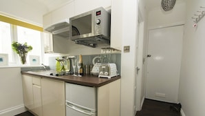 Cocina compacta equipada con microondas, tostadora y un refrigerador pequeño.