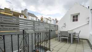 Un balcon avec une balustrade en métal, une table et une chaise.