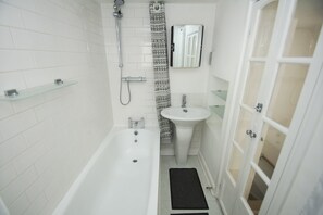 Une salle de bain équipée d’une baignoire, d’un lavabo, d’une douche et de toilettes.
