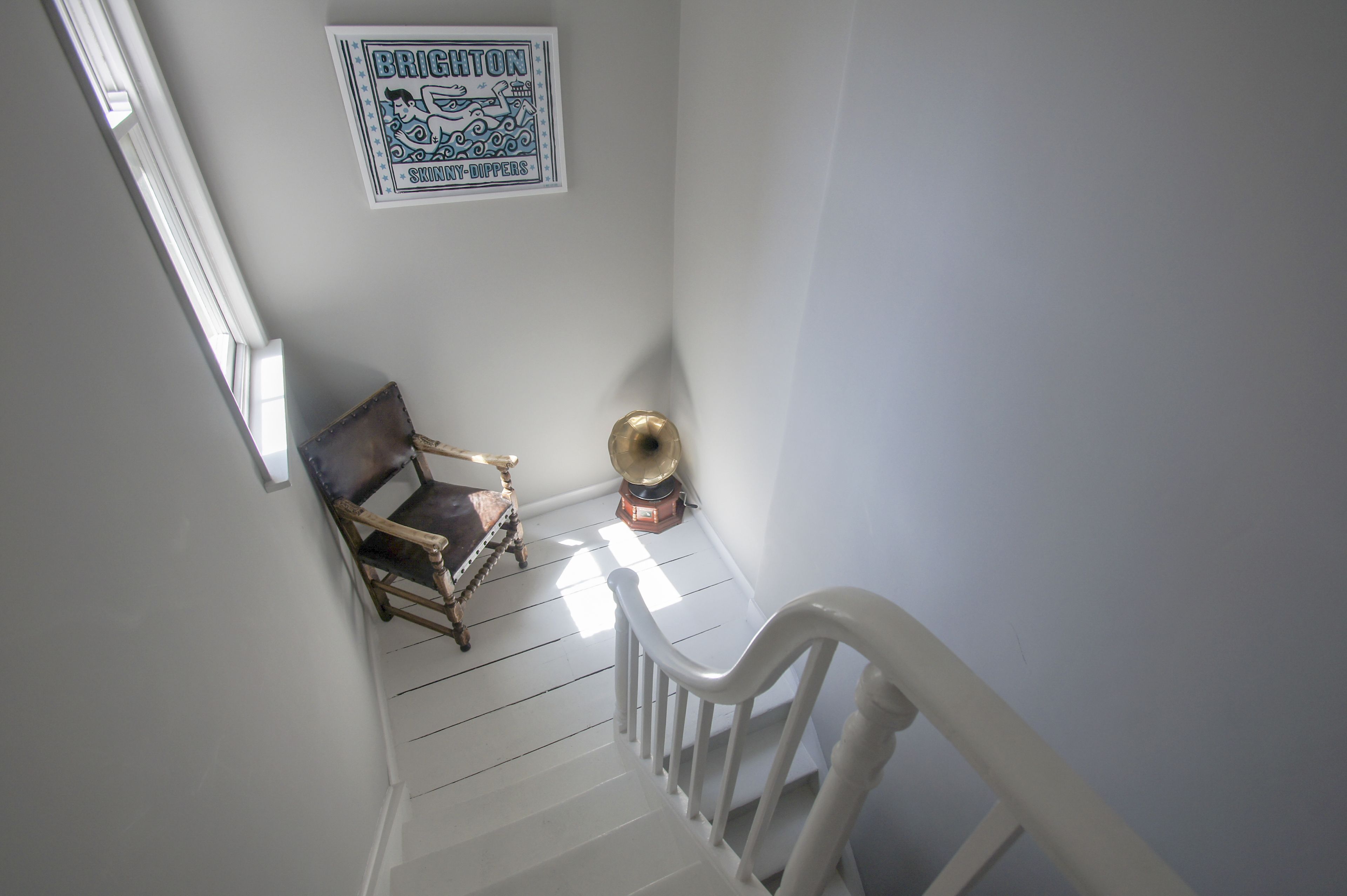 A staircase with a wooden chair and a gramophone on the landing.