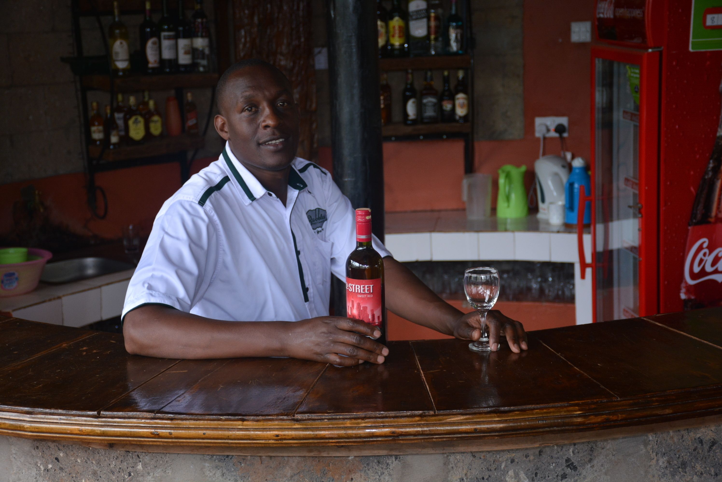 A bar setting with a bartender holding a bottle and a glass.