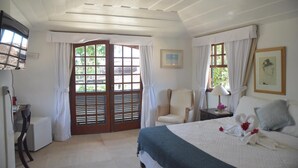 A bedroom with a bed, a chair, a desk, and a window with curtains. - Pousada Blanca Mar - Praia do Canto (Búzios)