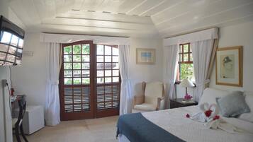 Quarto com cama, cadeira, escrivaninha e janela com cortinas.