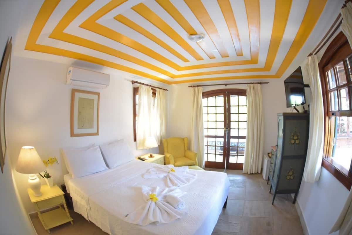 Une chambre d’hôtel avec un lit, une chaise, un bureau et une armoire.
