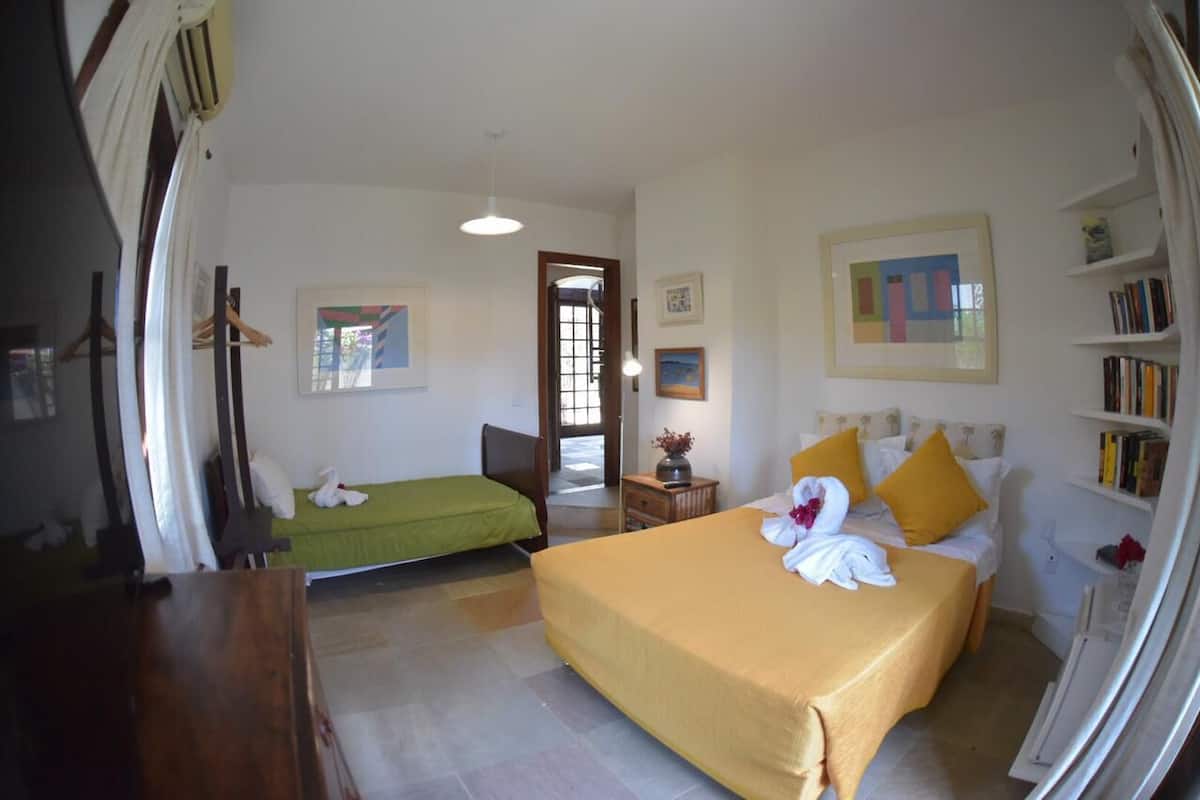 Une chambre d’hôtel avec un grand lit, un lit plus petit, un bureau et une bibliothèque.
