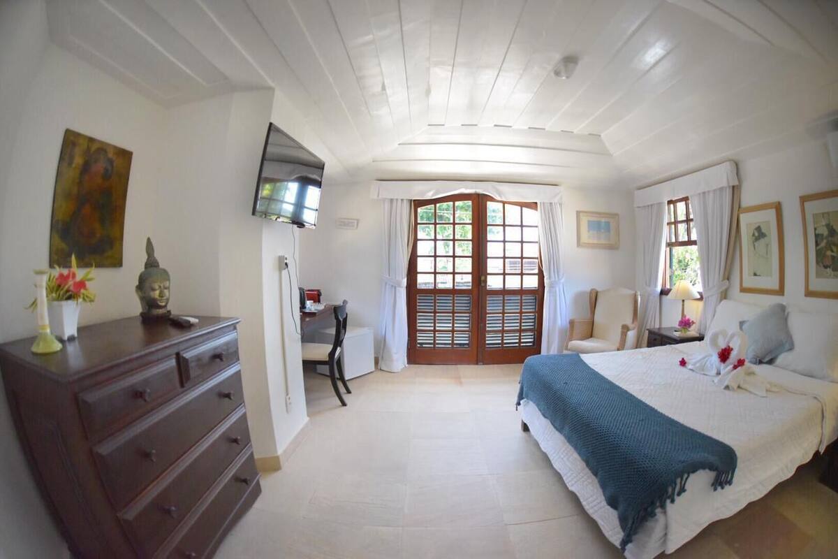 Une chambre à coucher avec un lit, un bureau, une chaise, une commode et un téléviseur fixé au mur.