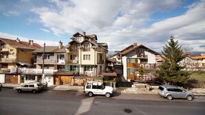 A street view with residential buildings, a cinema, and parked cars. - Winter Chalet fully catered - Pirin Adventures - Bansko - Bulgaria 8-12 people (Bansko)