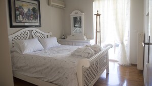 Ein Schlafzimmer mit Bett, Schminktisch, Spiegel und einem Fenster mit Vorhängen.