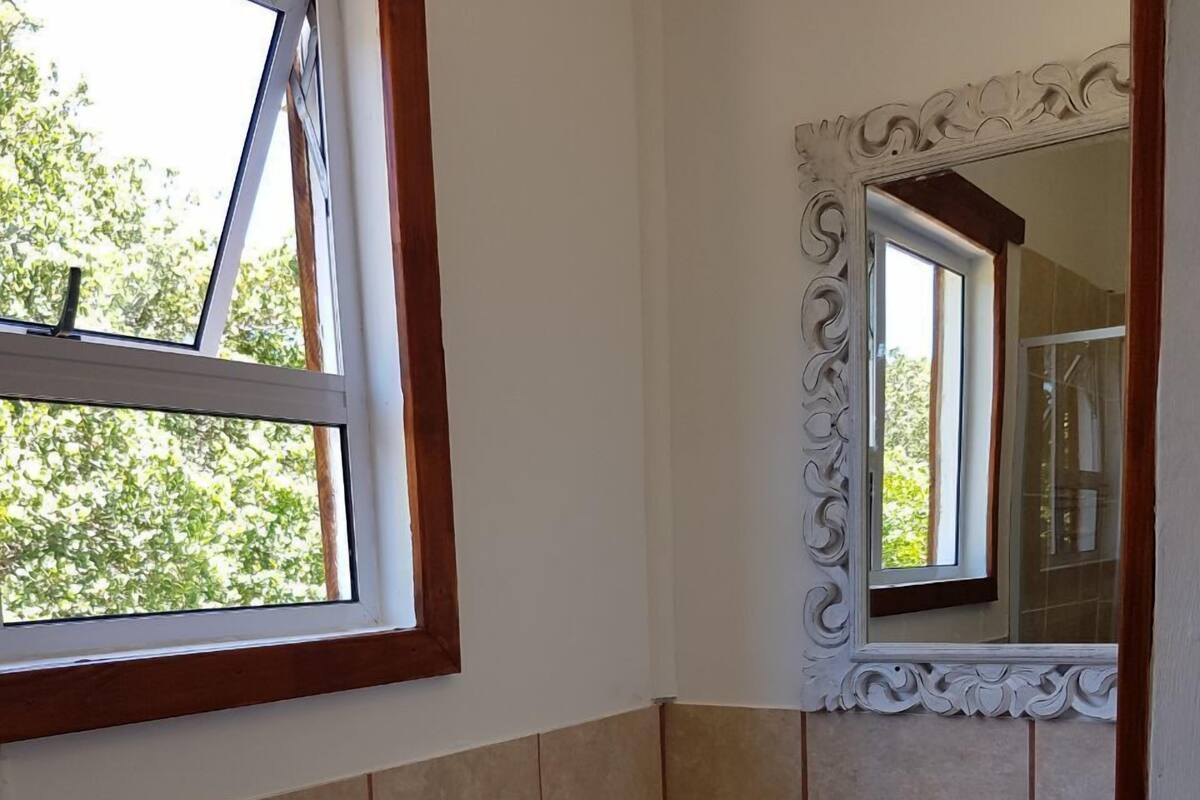 Een badkamer met een wastafel, toilet en een raam met uitzicht op bomen.