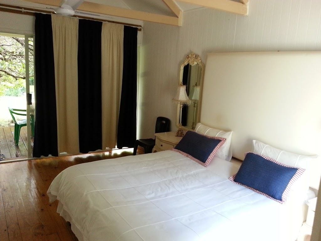 Un dormitorio con una cama grande, una mesita de noche, un espejo y vistas al exterior a través de una puerta corrediza.