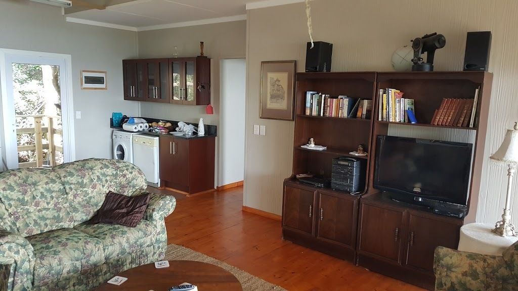 A living room with a floral sofa, a coffee table, a bookshelf, and a television.