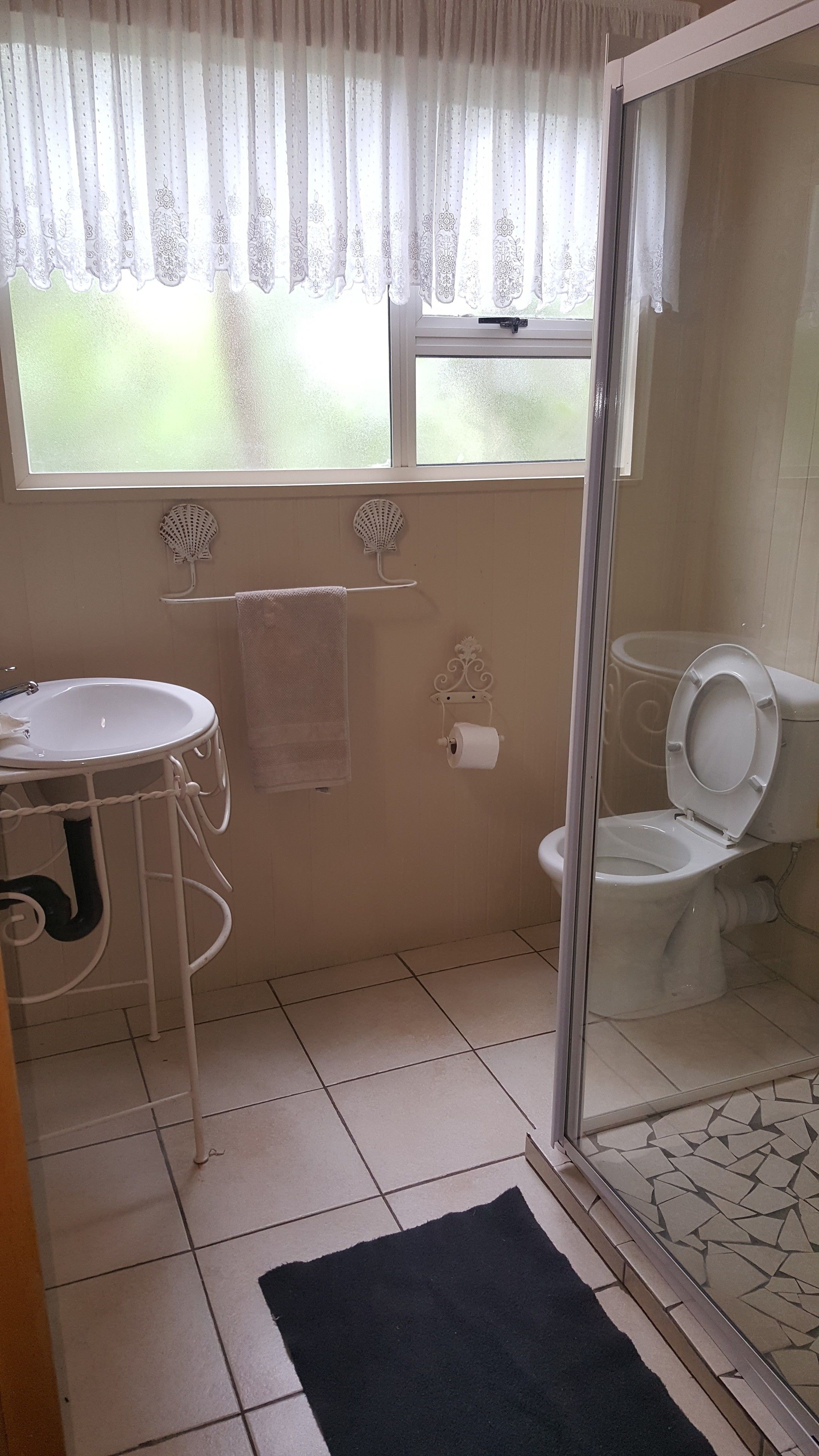 Un baño con inodoro, lavabo y ventana con cortinas.