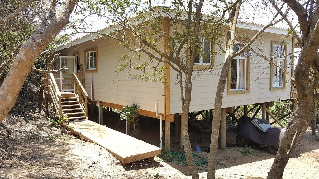 A treehouse with a wooden staircase leading to a platform, surrounded by trees.