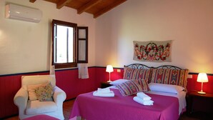 Une chambre avec deux lits, une chaise, une fenêtre et un climatiseur fixé au mur.