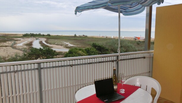 Un balcon avec une table, des chaises et un ordinateur portable.