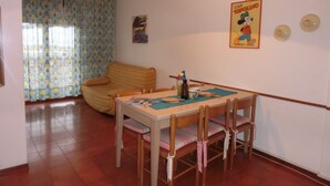 Un coin repas avec une table et des chaises en bois, un luminaire suspendu et une affiche accrochée au mur.